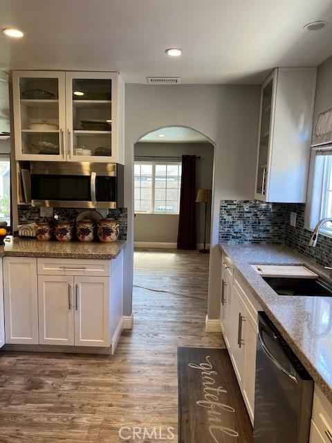 kitchen with arched walkways, stainless steel microwave, a sink, plenty of natural light, and dishwasher