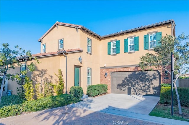 mediterranean / spanish home with brick siding, a tile roof, concrete driveway, stucco siding, and an attached garage