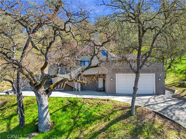 view of front facade with driveway, a front yard, an attached garage, and stucco siding