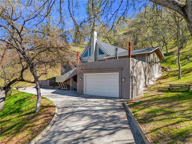 view of side of property with a yard, driveway, and stucco siding