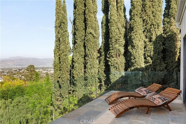 view of patio / terrace featuring a mountain view, a forest view, and fence