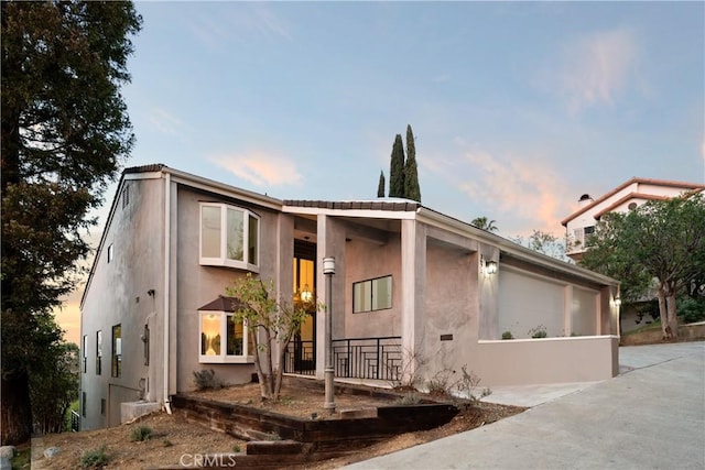 view of front of house with an attached garage, concrete driveway, and stucco siding