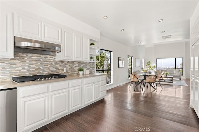 kitchen featuring gas cooktop, under cabinet range hood, light countertops, backsplash, and open shelves