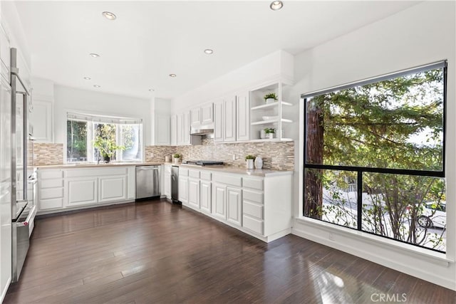 kitchen with stainless steel appliances, tasteful backsplash, light countertops, dark wood-type flooring, and white cabinets