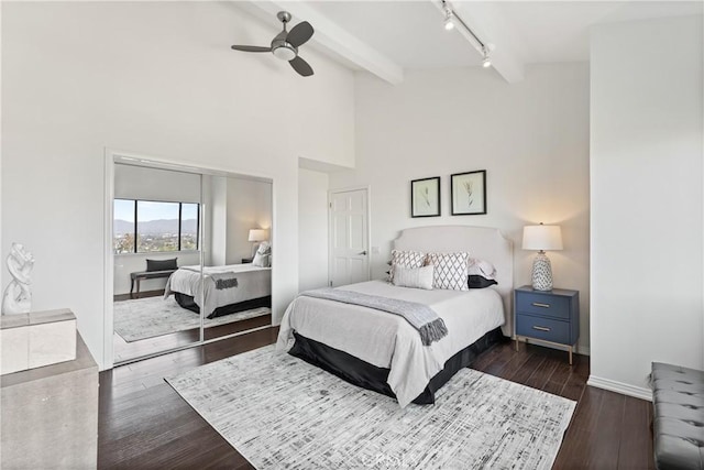 bedroom with baseboards, beamed ceiling, dark wood finished floors, and track lighting