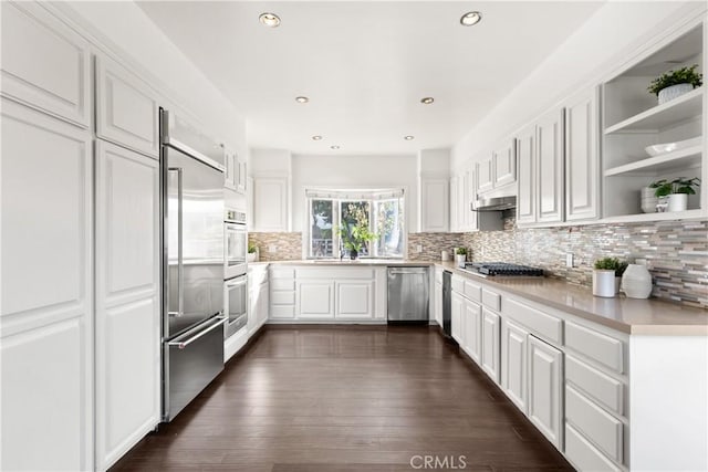 kitchen with stainless steel appliances, dark wood-style flooring, white cabinetry, light countertops, and open shelves