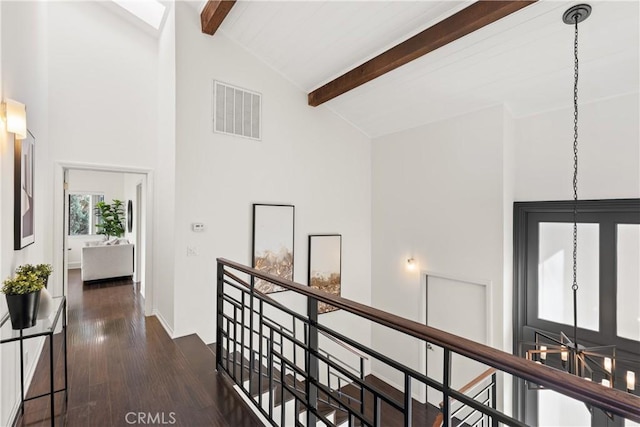 hall with dark wood-style flooring, beam ceiling, visible vents, an upstairs landing, and high vaulted ceiling