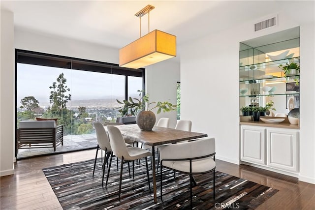 dining space featuring dark wood finished floors, visible vents, and baseboards