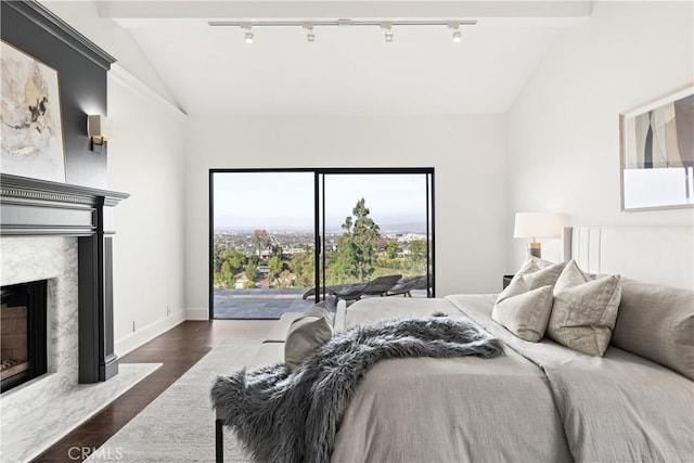 bedroom with lofted ceiling, baseboards, wood finished floors, and a high end fireplace