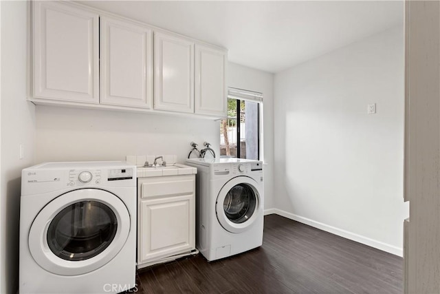 laundry room with cabinet space, baseboards, dark wood finished floors, washing machine and dryer, and a sink