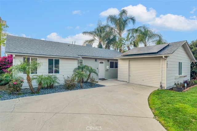 ranch-style home featuring a shingled roof, driveway, an attached garage, and solar panels