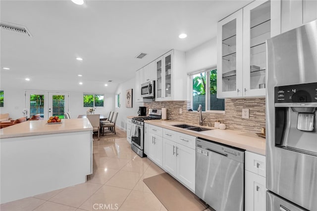 kitchen featuring light tile patterned floors, tasteful backsplash, visible vents, appliances with stainless steel finishes, and a sink