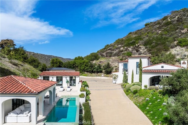 back of property featuring a patio, stucco siding, a mountain view, an outdoor pool, and a tiled roof