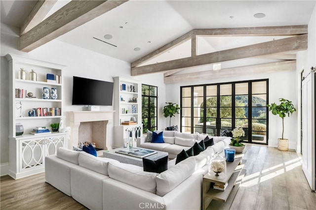 living room with a fireplace, plenty of natural light, beamed ceiling, and wood finished floors
