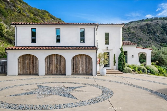 mediterranean / spanish-style home with concrete driveway, an attached garage, a tile roof, and stucco siding