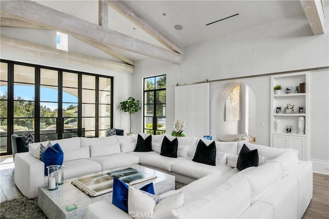 living area with arched walkways, high vaulted ceiling, beamed ceiling, and wood finished floors