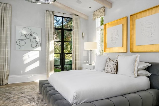 bedroom with multiple windows, baseboards, wood finished floors, and beamed ceiling