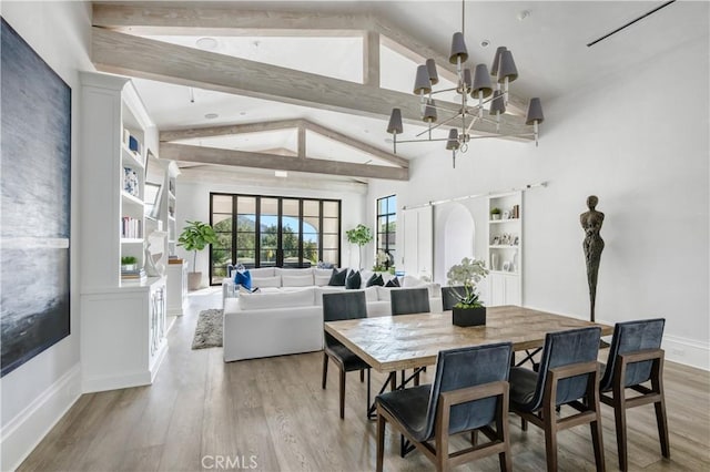 dining room with a chandelier, arched walkways, beam ceiling, and wood finished floors