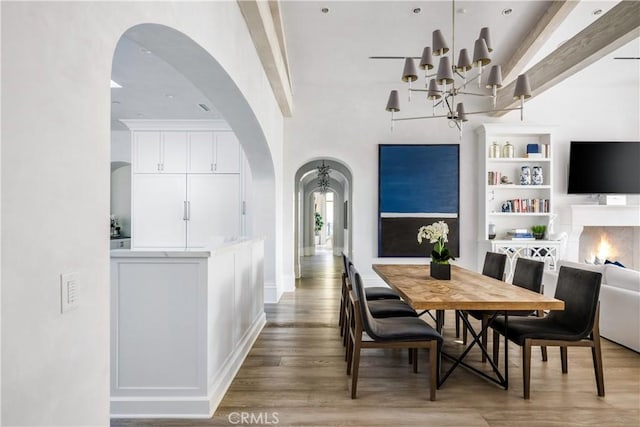 dining room featuring a chandelier, arched walkways, and light wood-style flooring