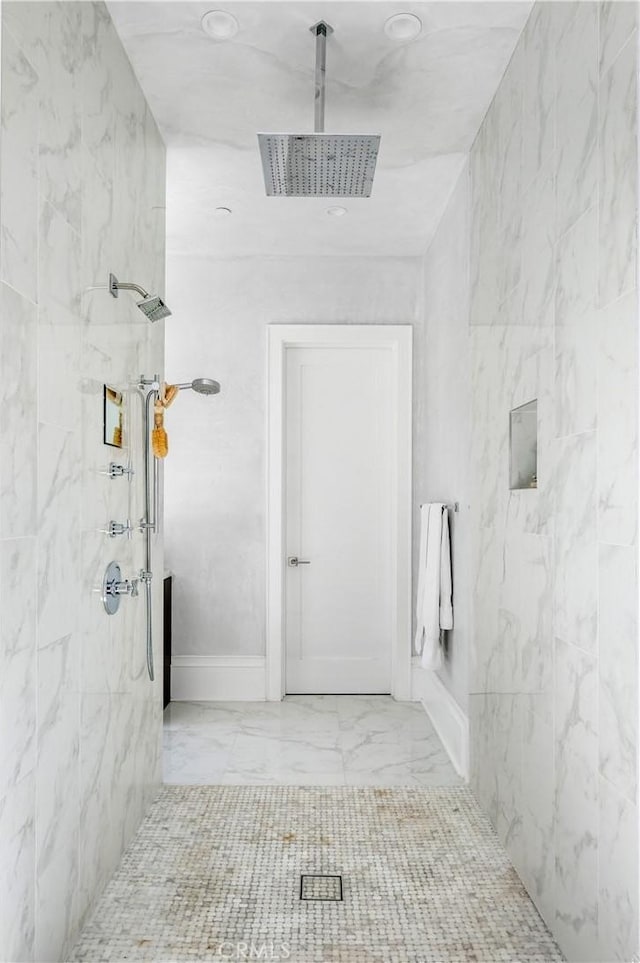 full bathroom featuring marble finish floor and a tile shower