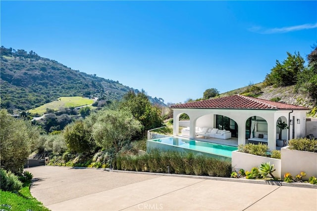outdoor pool featuring a patio area, a mountain view, fence, and an outdoor hangout area