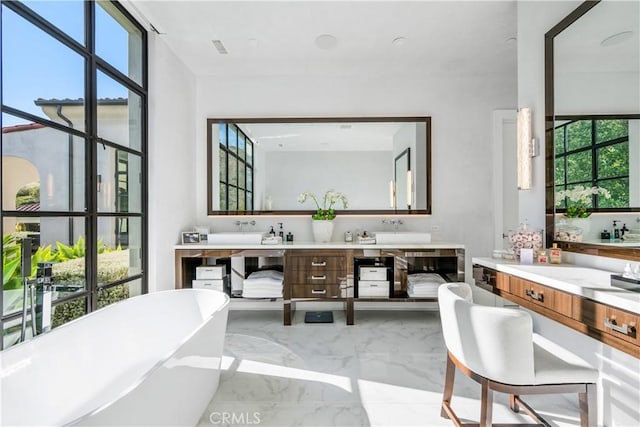 bathroom with marble finish floor, visible vents, a freestanding tub, and double vanity