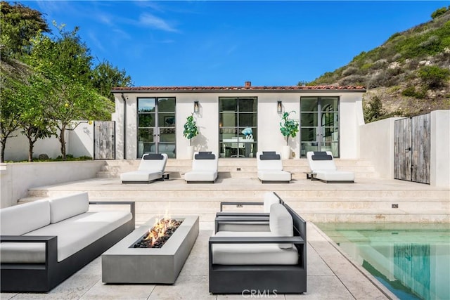 view of patio / terrace featuring french doors, an outdoor living space with a fire pit, and a fenced backyard