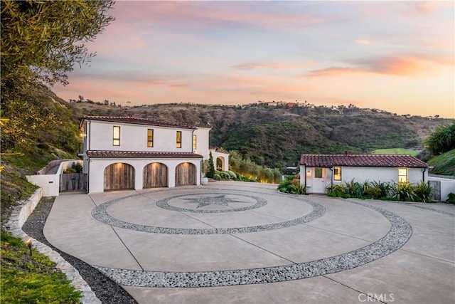 mediterranean / spanish-style house with fence, curved driveway, a tiled roof, and stucco siding