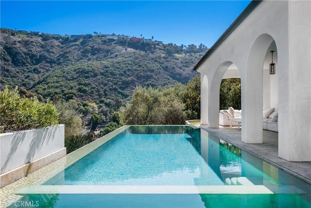 view of pool with an infinity pool and a patio area