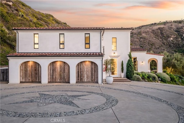 mediterranean / spanish-style house featuring a garage, concrete driveway, a tile roof, and stucco siding
