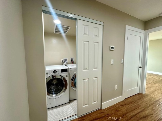 laundry area with visible vents, baseboards, laundry area, wood finished floors, and washer and dryer