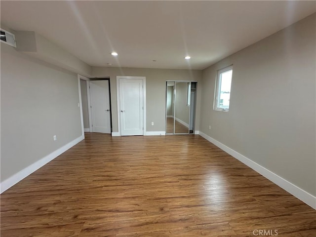 unfurnished bedroom with visible vents, two closets, wood finished floors, recessed lighting, and baseboards