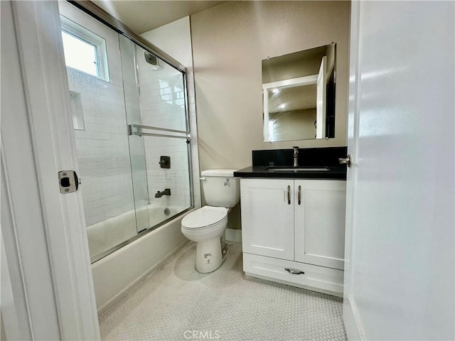 full bath featuring tile patterned flooring, toilet, vanity, and bath / shower combo with glass door