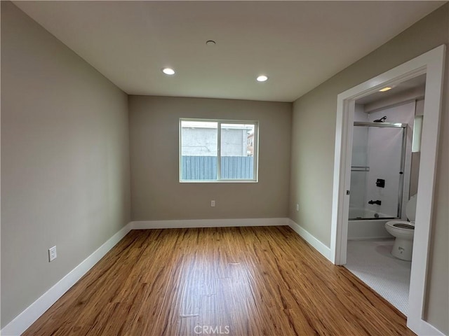 unfurnished bedroom with recessed lighting, wood finished floors, and baseboards