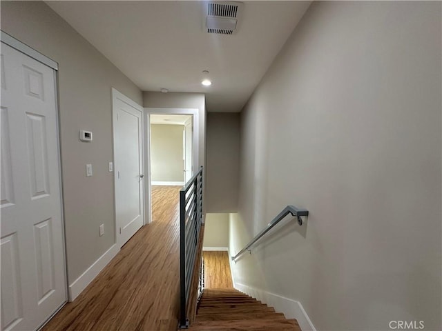 staircase featuring wood finished floors, visible vents, and baseboards