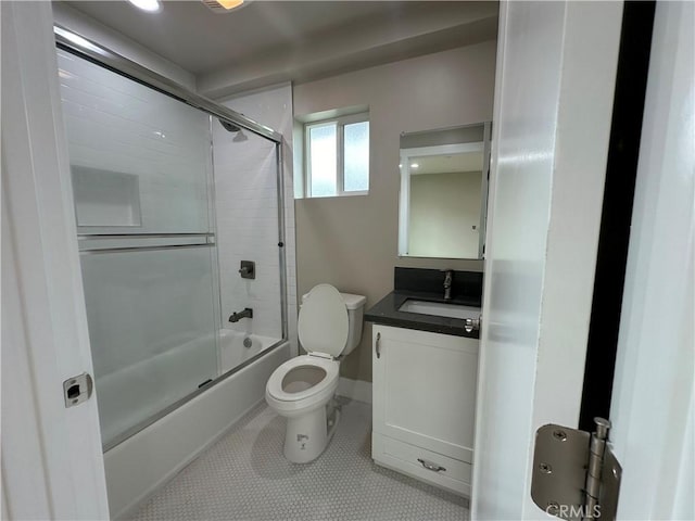 full bath with tile patterned flooring, toilet, vanity, and bath / shower combo with glass door