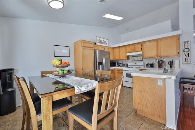 kitchen with under cabinet range hood, a peninsula, a sink, white range with gas cooktop, and stainless steel refrigerator with ice dispenser