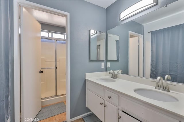 bathroom featuring double vanity, tile patterned flooring, a sink, and a shower with shower door