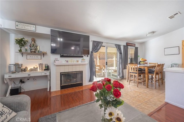 living area with vaulted ceiling, a fireplace, wood finished floors, and visible vents