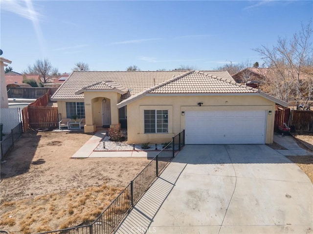 mediterranean / spanish home featuring driveway, a garage, a tiled roof, fence, and stucco siding