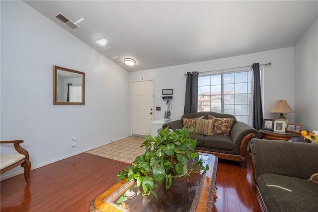 living room with lofted ceiling, baseboards, visible vents, and wood finished floors