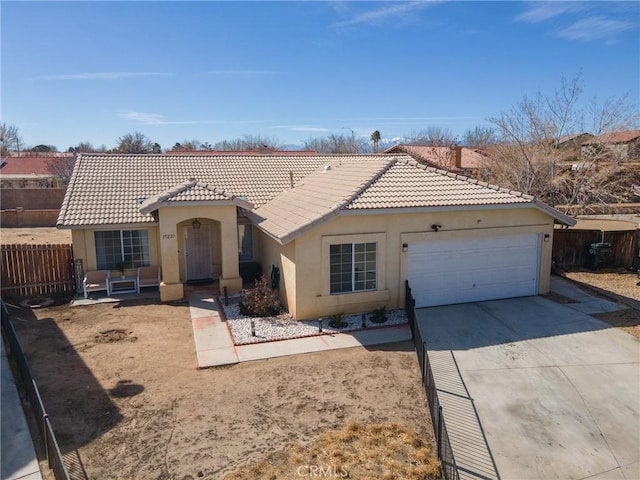 mediterranean / spanish home featuring driveway, a tile roof, an attached garage, fence, and stucco siding