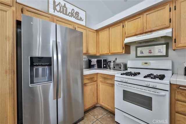 kitchen with tile countertops, under cabinet range hood, white gas range, and stainless steel fridge with ice dispenser