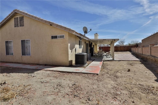 rear view of property with stucco siding, a fenced backyard, cooling unit, and a patio