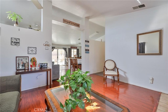 living room with wood finished floors, visible vents, and baseboards