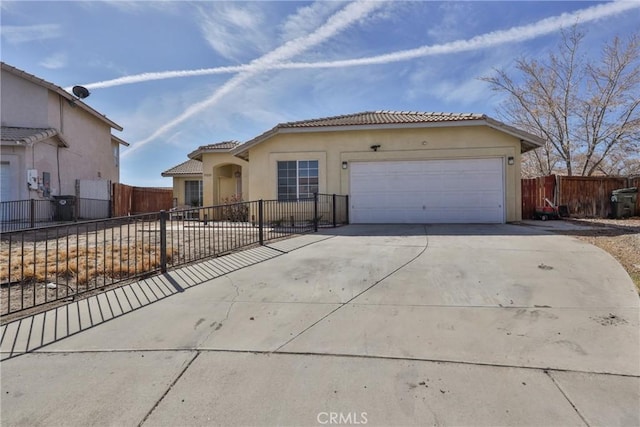 mediterranean / spanish house with a garage, concrete driveway, a tiled roof, fence, and stucco siding