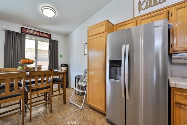 kitchen featuring tile counters, stainless steel fridge, and light tile patterned flooring