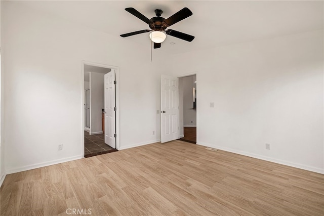 unfurnished bedroom with baseboards, ensuite bath, ceiling fan, and light wood-style floors