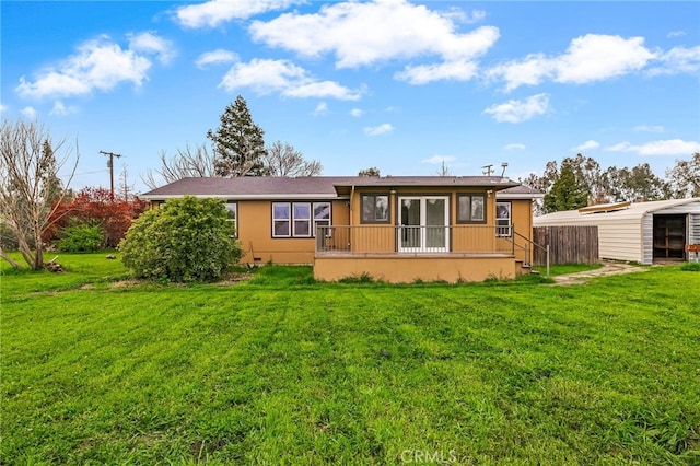 back of house with stucco siding, fence, and a lawn