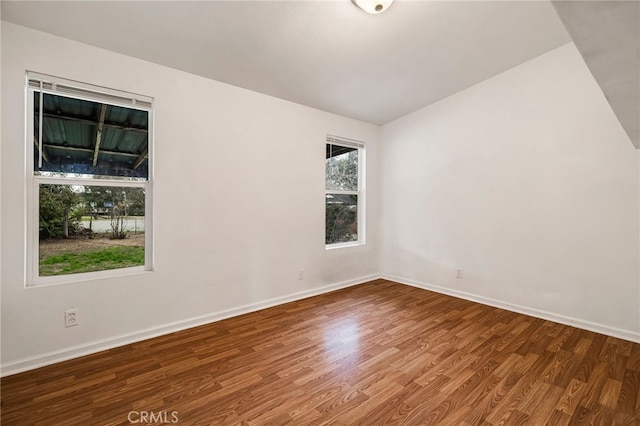 unfurnished room with baseboards, wood finished floors, and vaulted ceiling